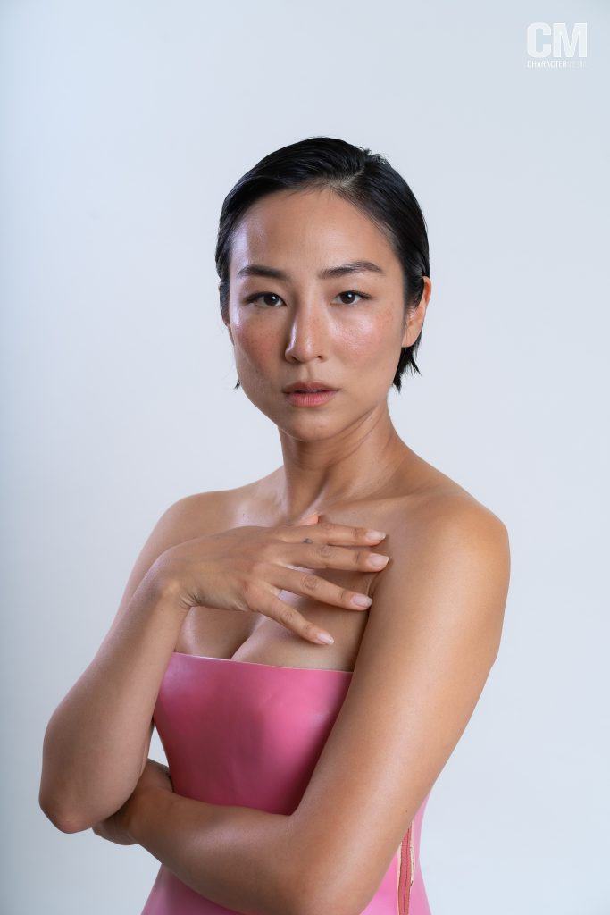 Greta Lee posing in front of a white background.