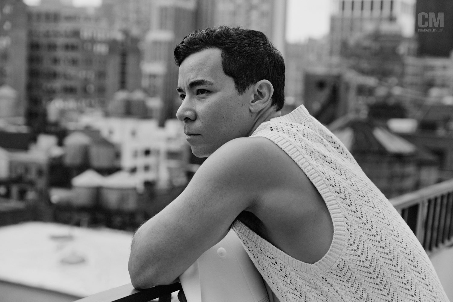 A photo of Conrad Ricamora posing in front of the New York City skyline.