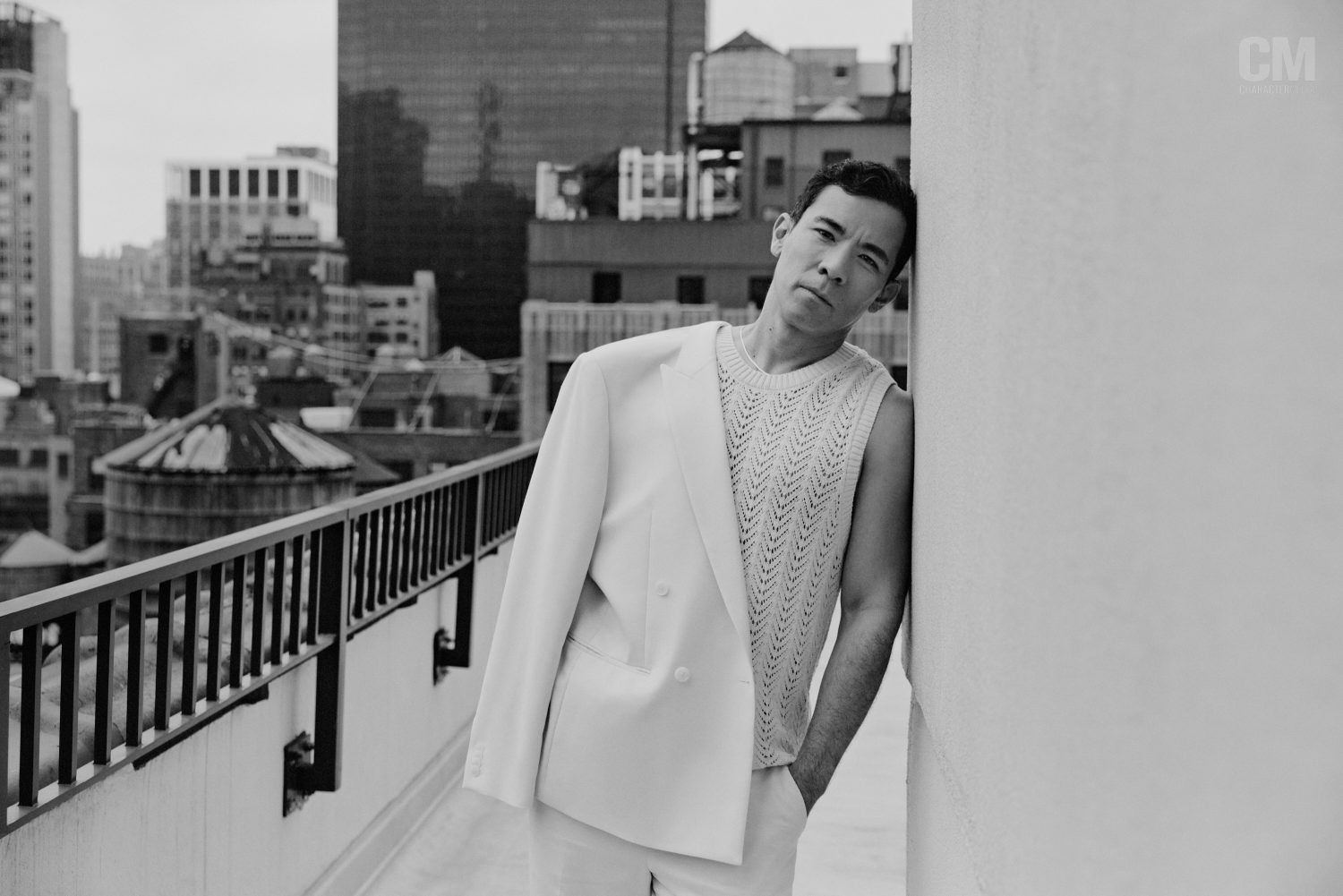 A photo of Conrad Ricamora posing in front of the New York City skyline.