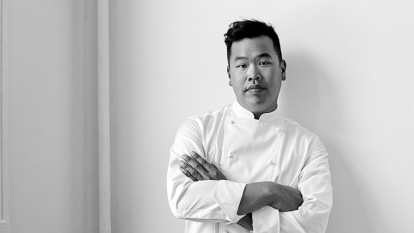 Top Chef winner Buddha posing in a black and white photo in his chef uniform