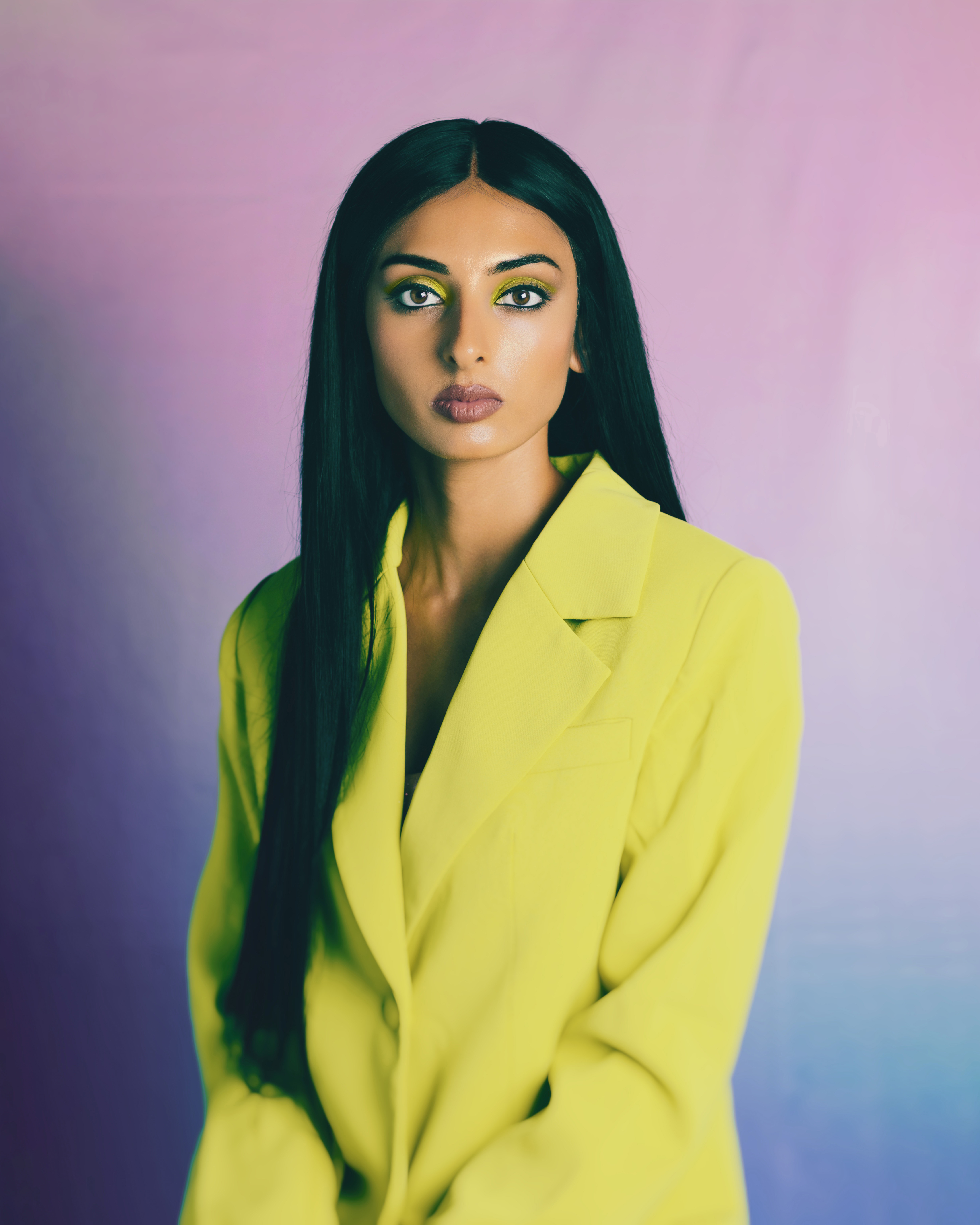 Filmmaker Mahnoor Euceph sits in front of a pink-purple gradient background in a yellow pantsuit.