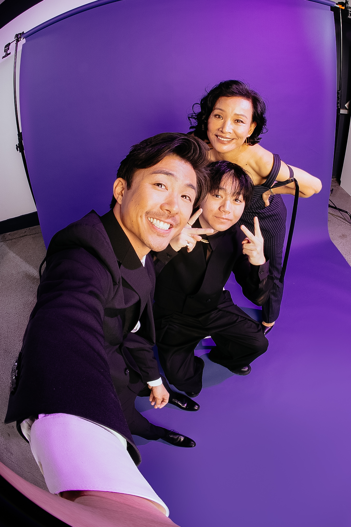 Sean Wang, Izaac Wang and Joan Chen pose in front of a purple backdrop.